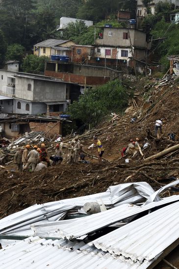 Bombeiros, moradores e voluntários trabalham no local do deslizamento no Morro da Oficina, após a chuva que castigou Petrópolis, na região serrana fluminense