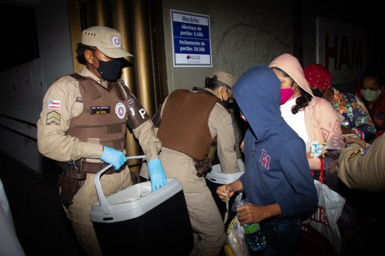 Policiais distribuem refeições para pacientes que aguardam em fila de hospital