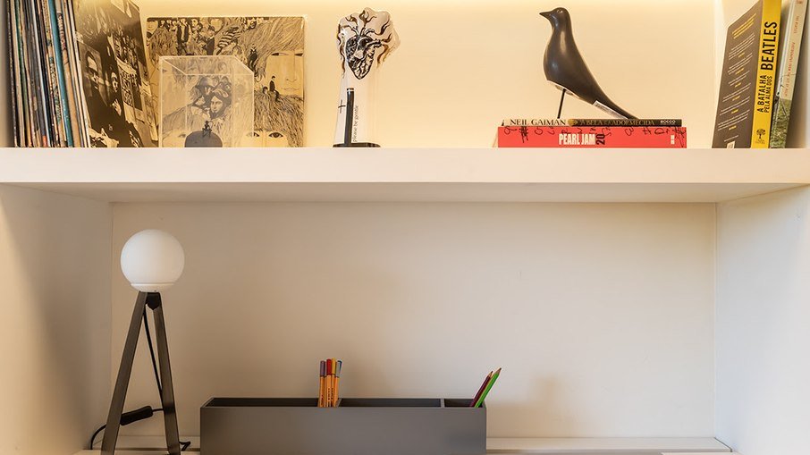 O cantinho do home office deste apartamento executado por Marina Carvalho ganhou fitas de LED no forro e nas prateleiras para reforçar a iluminação durante as atividades profissionais. 