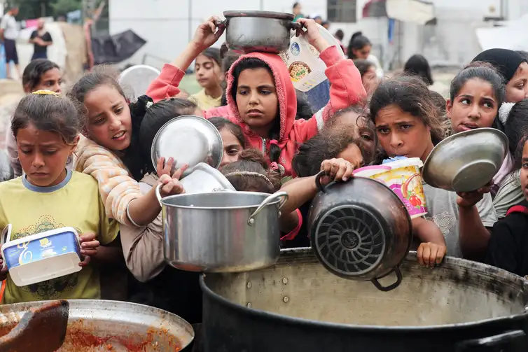 Palestinos aguardam para receber comida preparada por uma cozinha comunitária, em Nuseirat, Faixa de Gaza
08/04/2025
REUTERS/Ramadan Abed