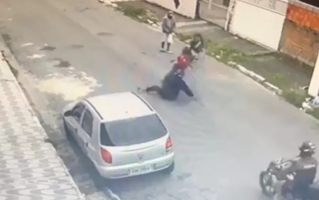Motociclista cai ao empinar e moto atinge homem na rua no litoral; veja o vídeo